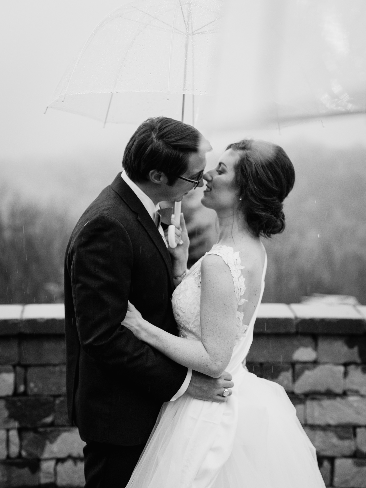 Bride and groom kiss in the rain at Irvine Estate
