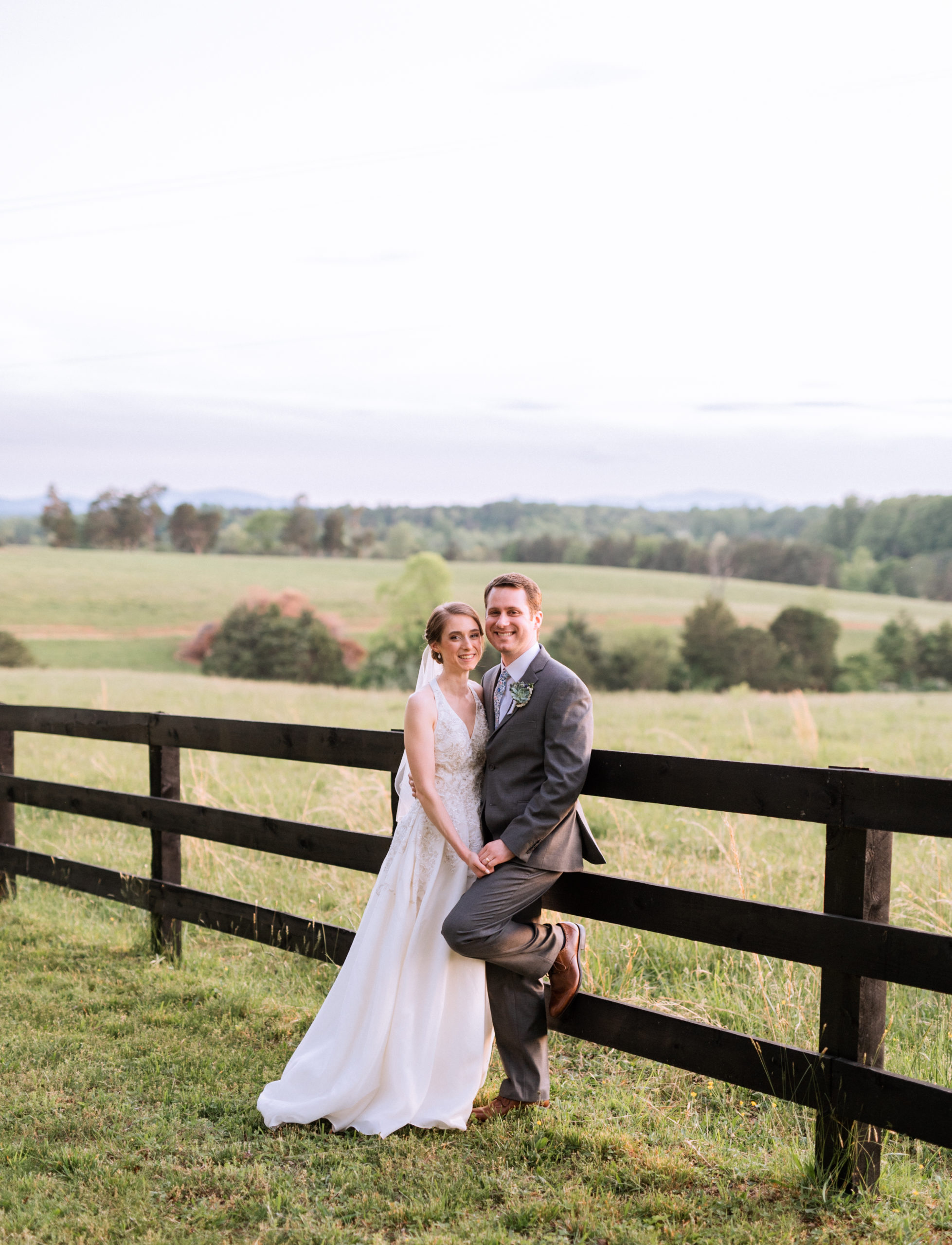 bride and groom pose along fence at Charlottesville, VA wedding reception