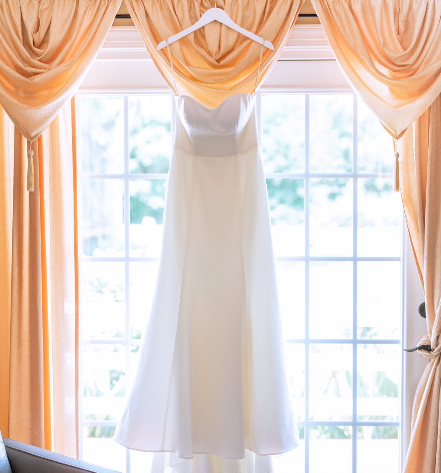 Bride's wedding gown hanging in window before wedding ceremony in Richmond, Virginia