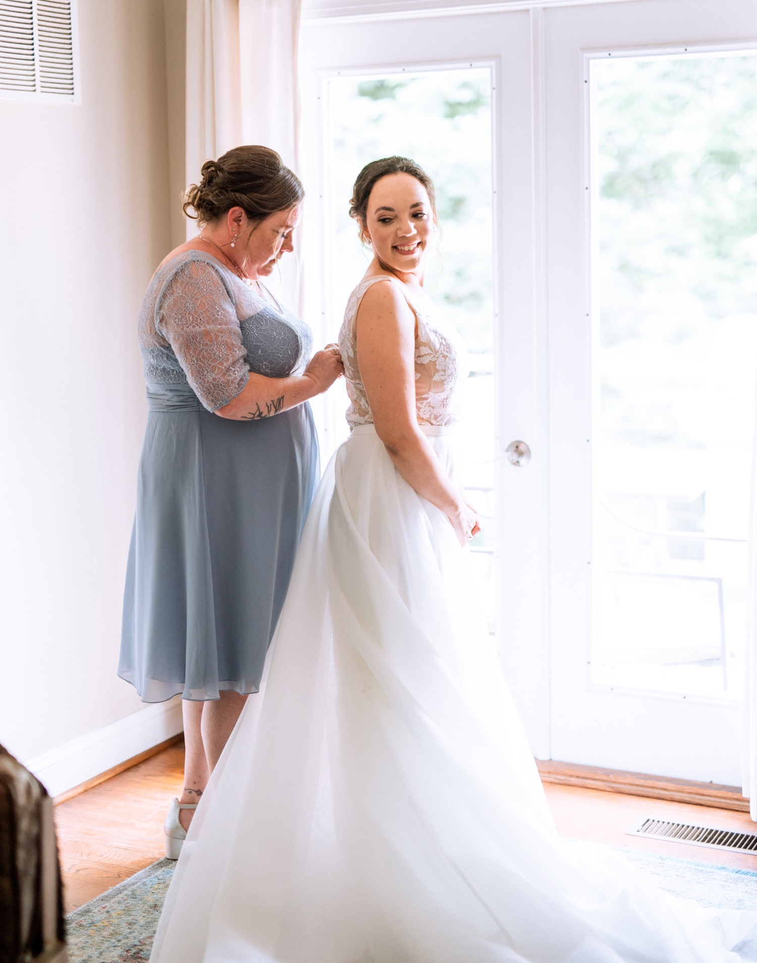 Mother helping daughter button up her dress before her wedding ceremony at James Monroe's Highland in Charlottesville, VA
