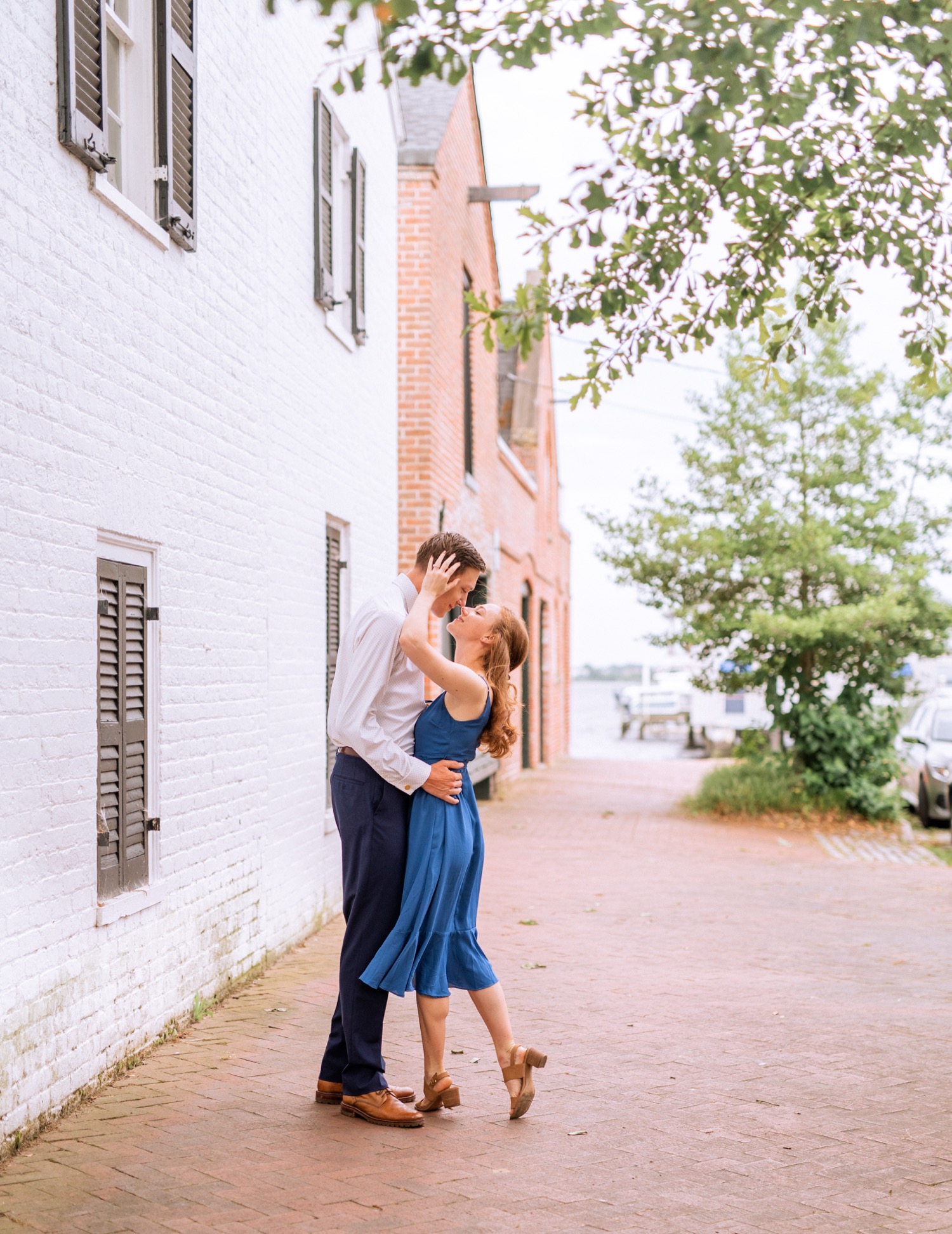 engaged couple share a kiss during engagement shoot in the freeman historic district in norfolk virginia