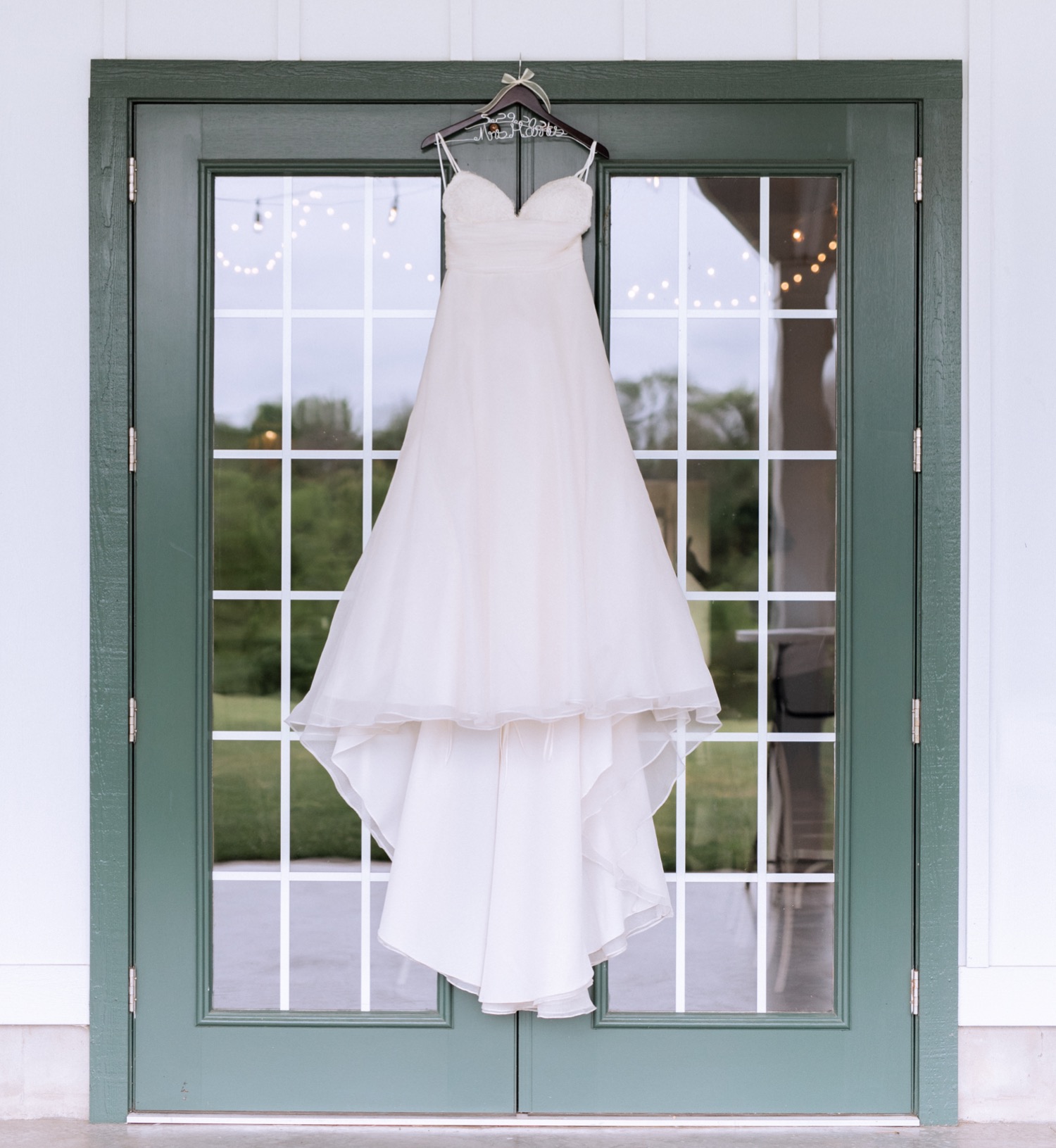 wedding dress hanging from barn doors before wedding ceremony