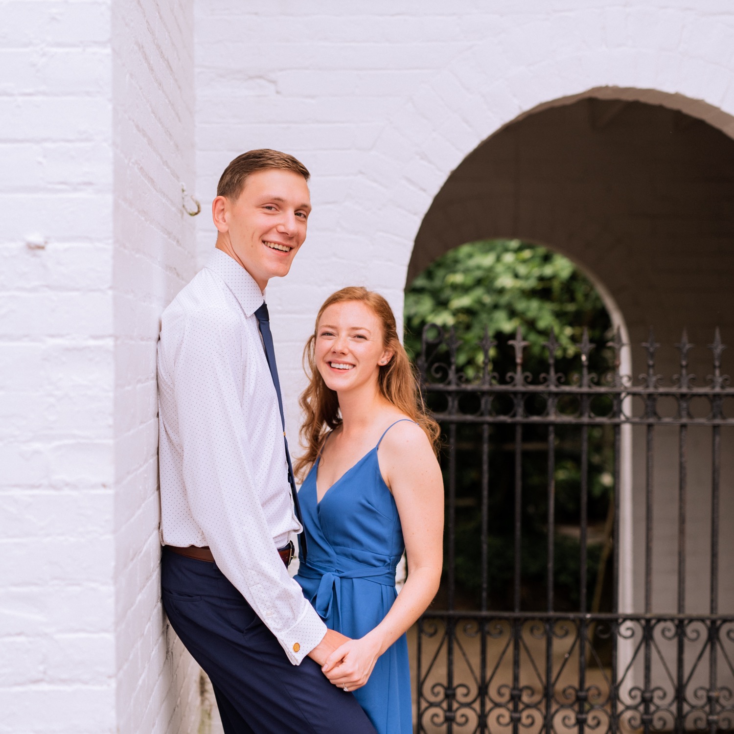 engaged couple hold hands and look at camera smiling during engagement shoot in the freeman historic district in norfolk virginia