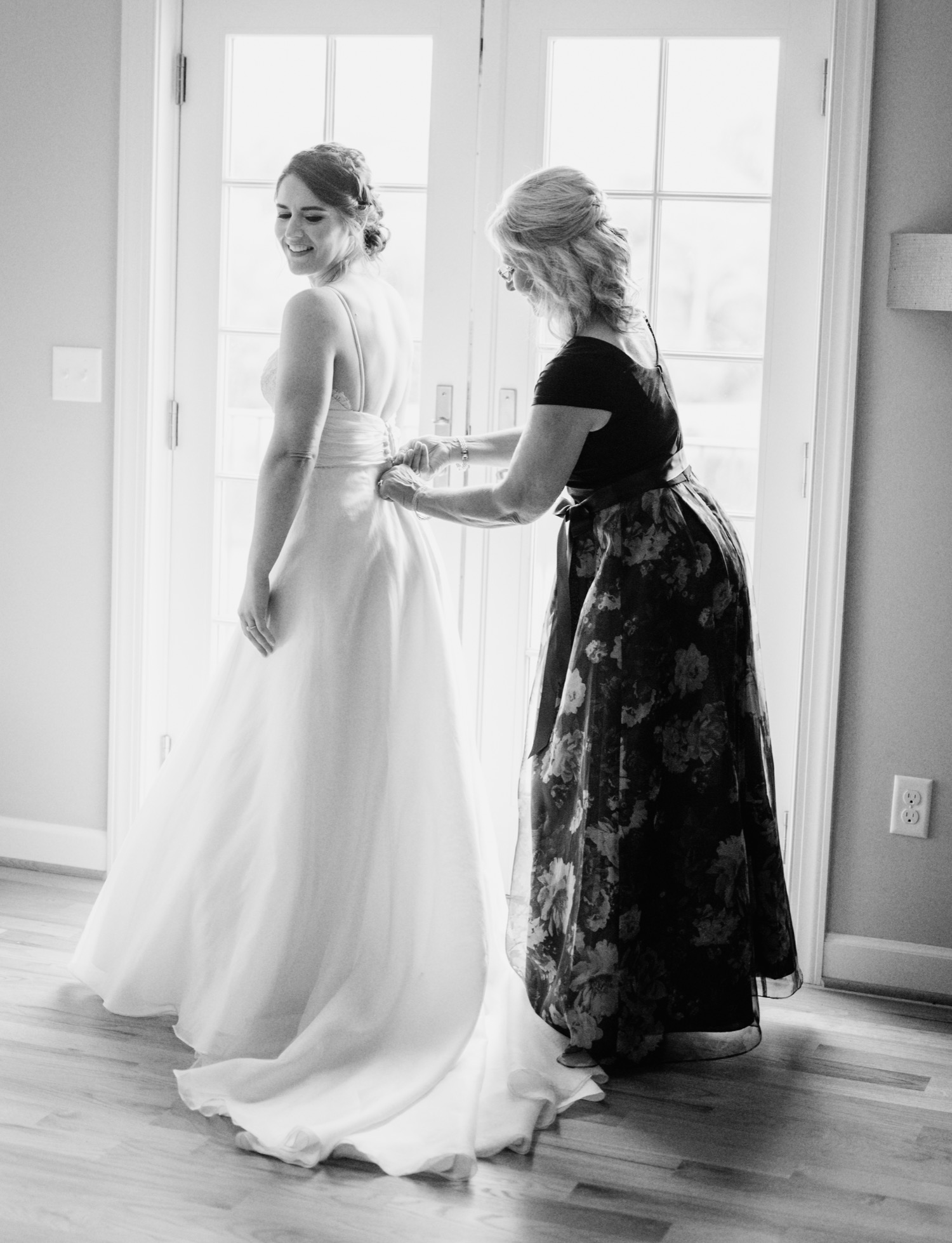 mother of the bride helping her daughter finish getting ready before her first look