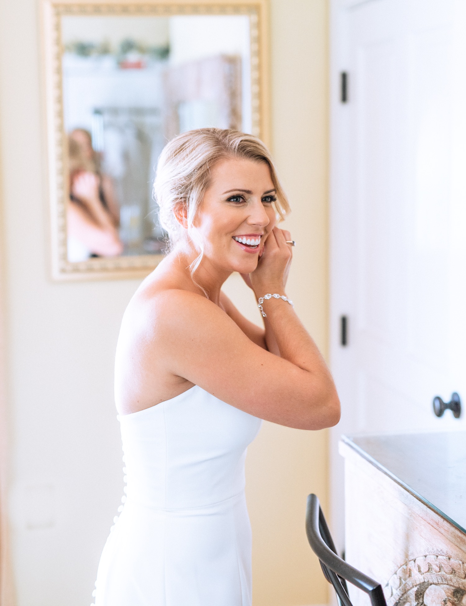 Bride putting in earrings as her final touch before she heads to her wedding ceremony in Richmond, Virginia summer wedding