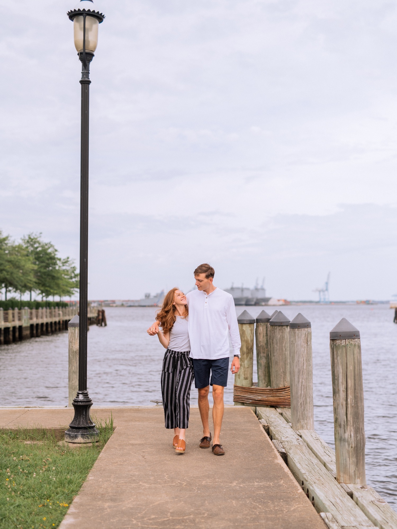 engaged couple hold each other close on waterfront during engagement shoot in the freeman historic district in norfolk virginia
