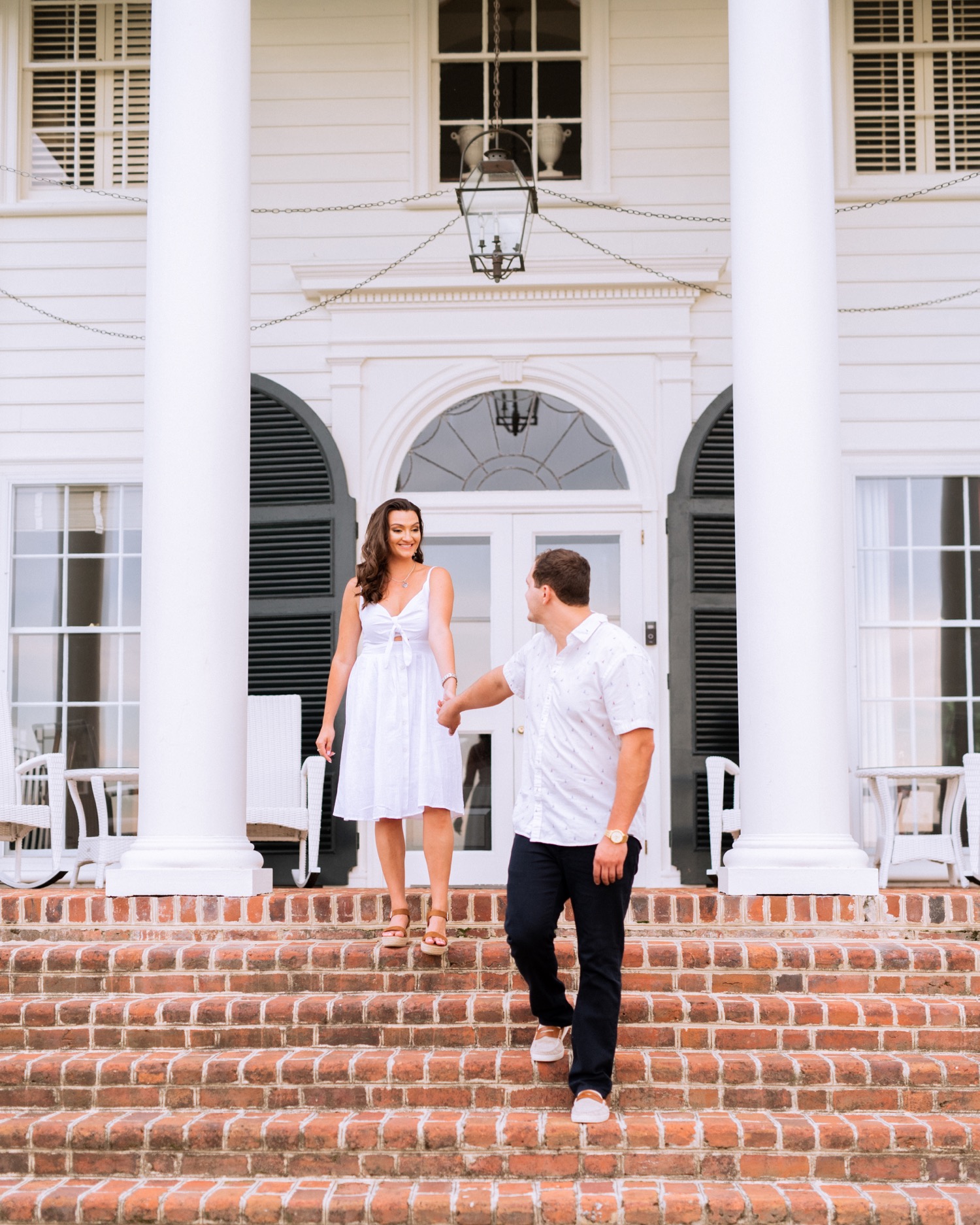 engaged couple holding hands and walking down the front staircase at the cumberland estate in richmond virginia