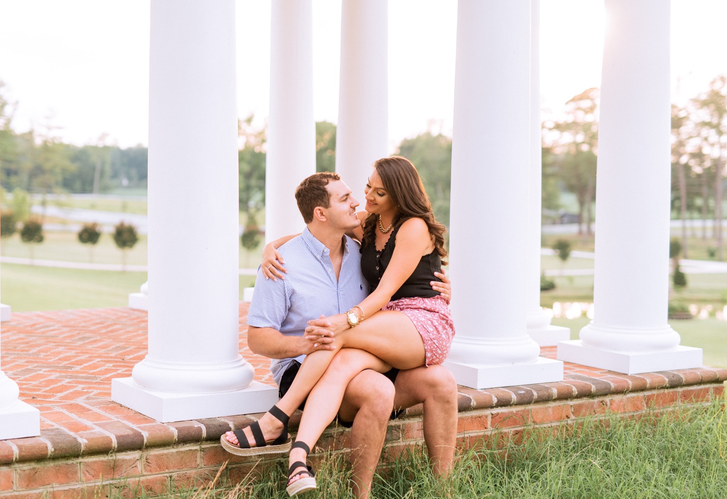 engaged couple cuddling in front of pillars at the cumberland estate in richmond virginia