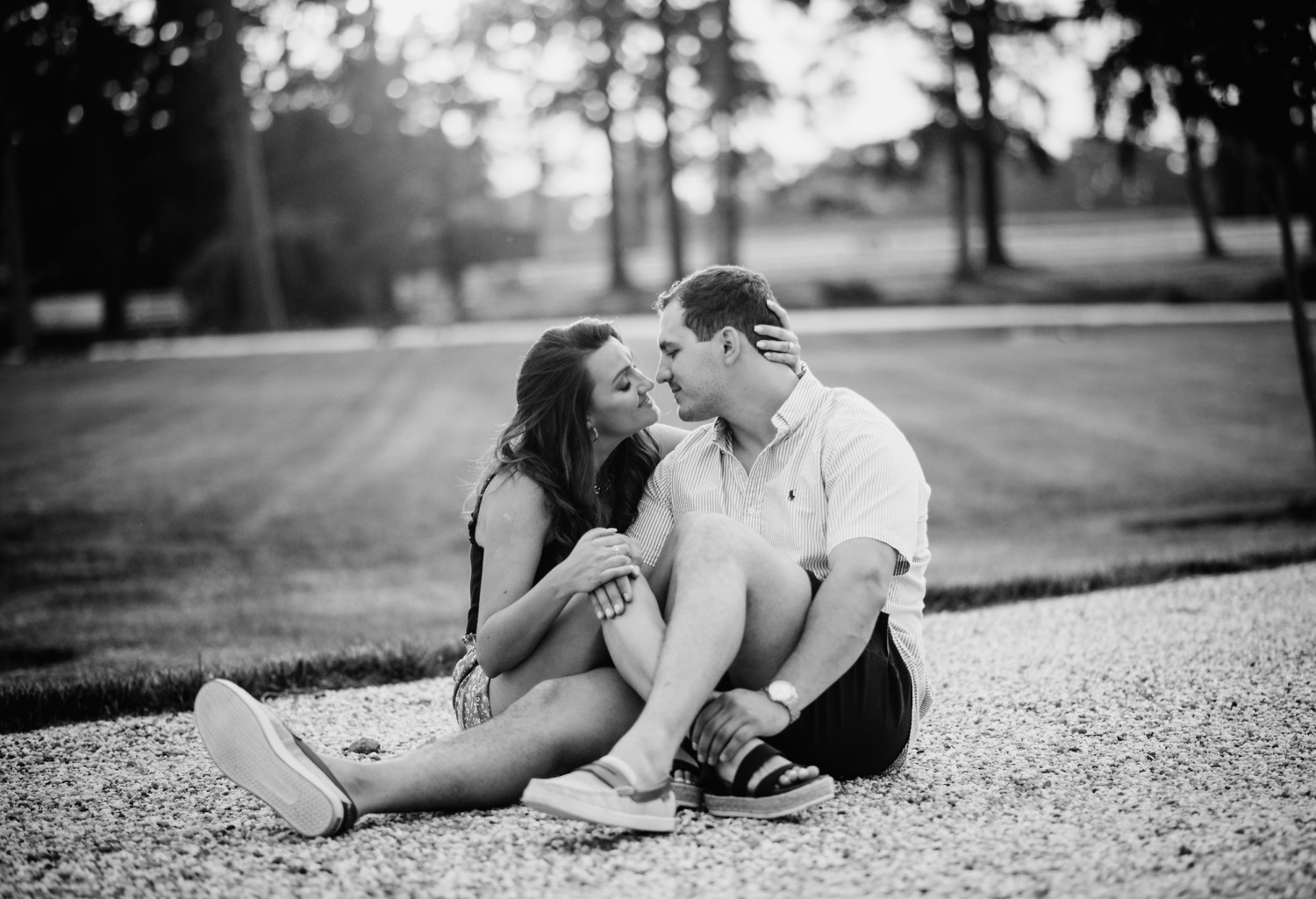 engaged couple holding each other close and leaning in for a kiss in front of the lake at the cumberland estate in richmond Virginia 