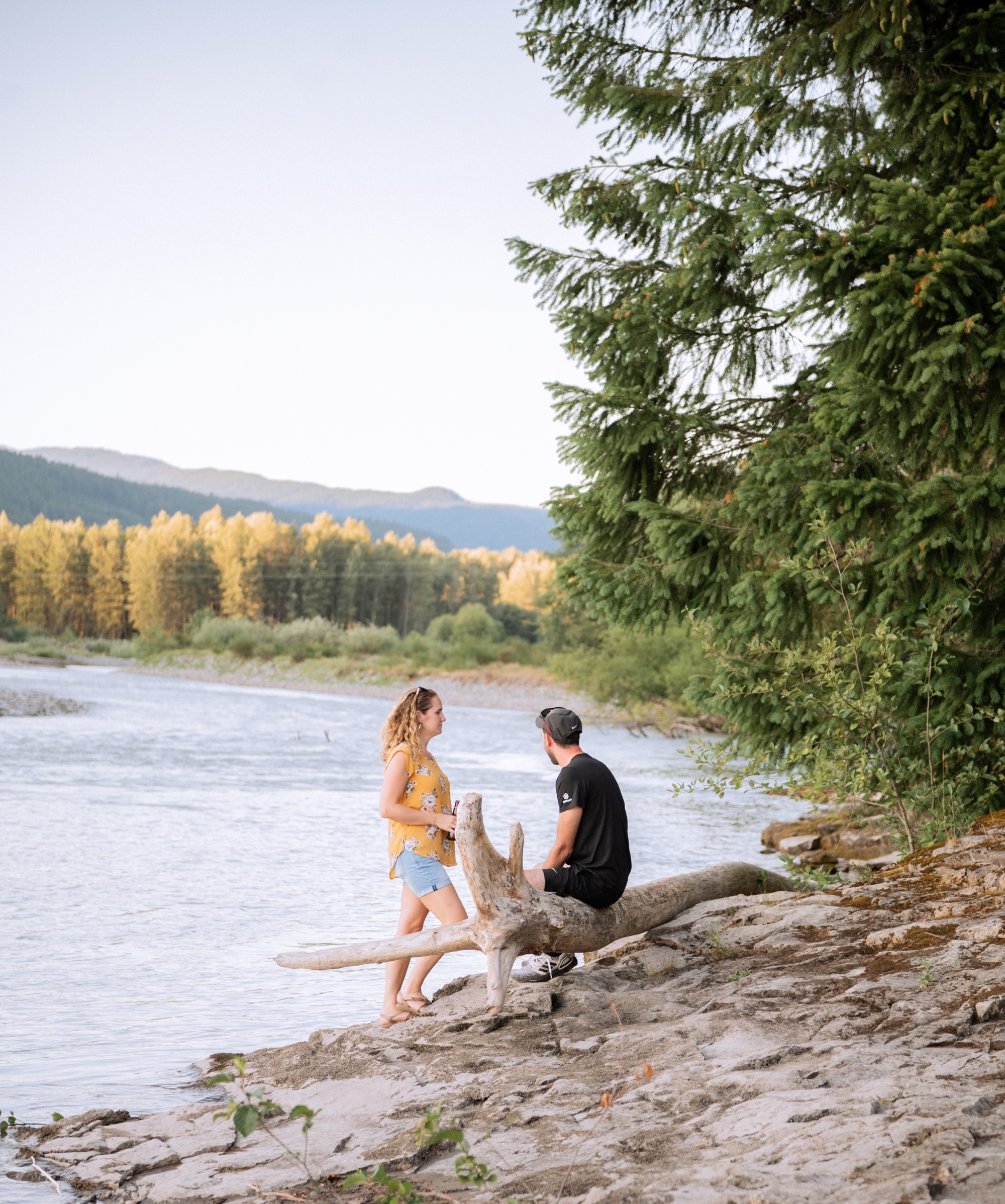 engaged couple talking on the shore of the lake at the base of mt rainier