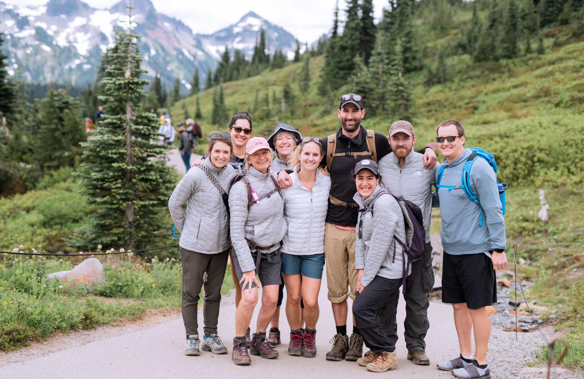 engaged couple with friends and family at the base of mt rainier wearing hiking clothes and shoes