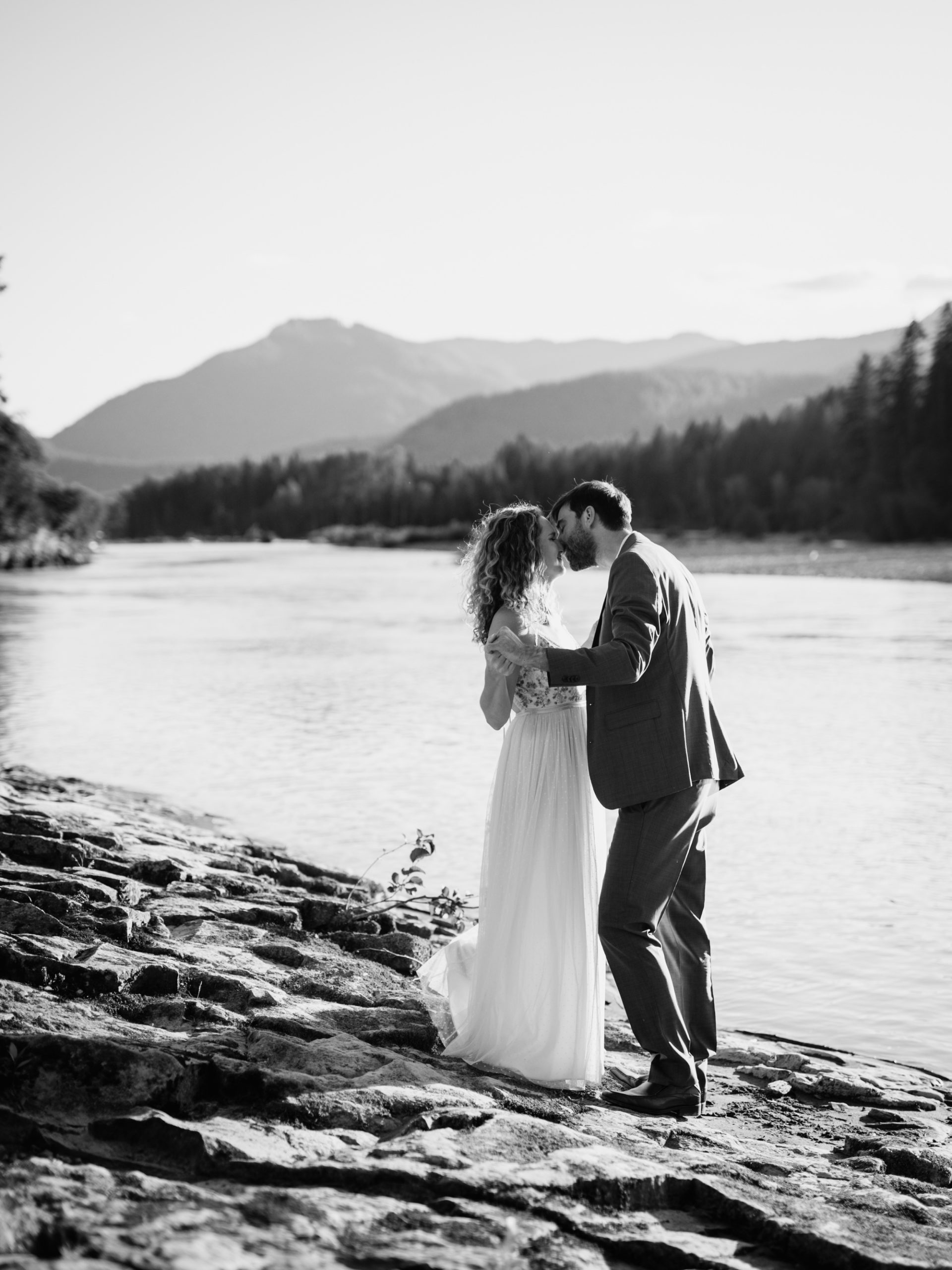 bride and groom kissing along the waterfront in mt rainier national park