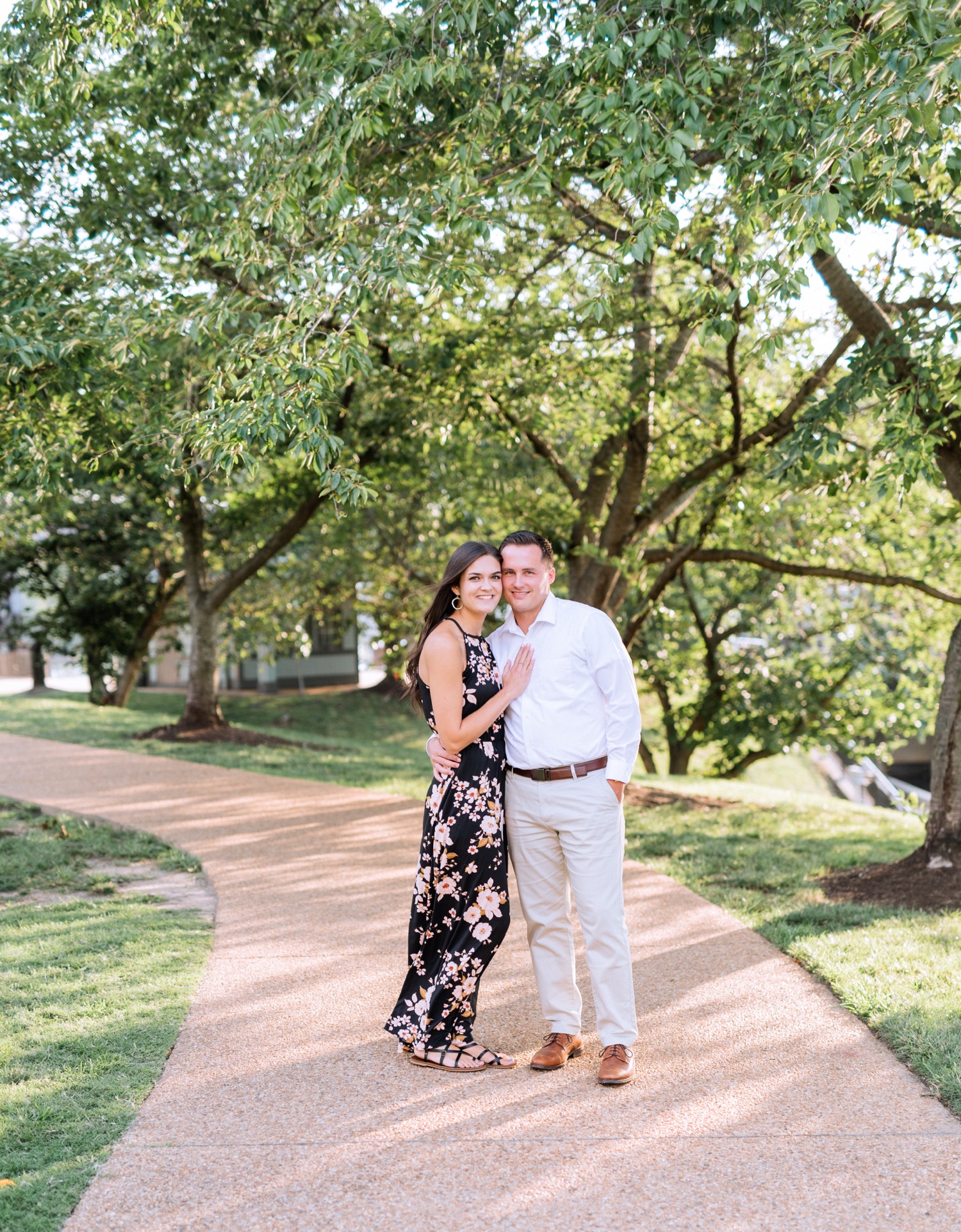 engaged couple hugging under the trees along a path in charlottesville virginia