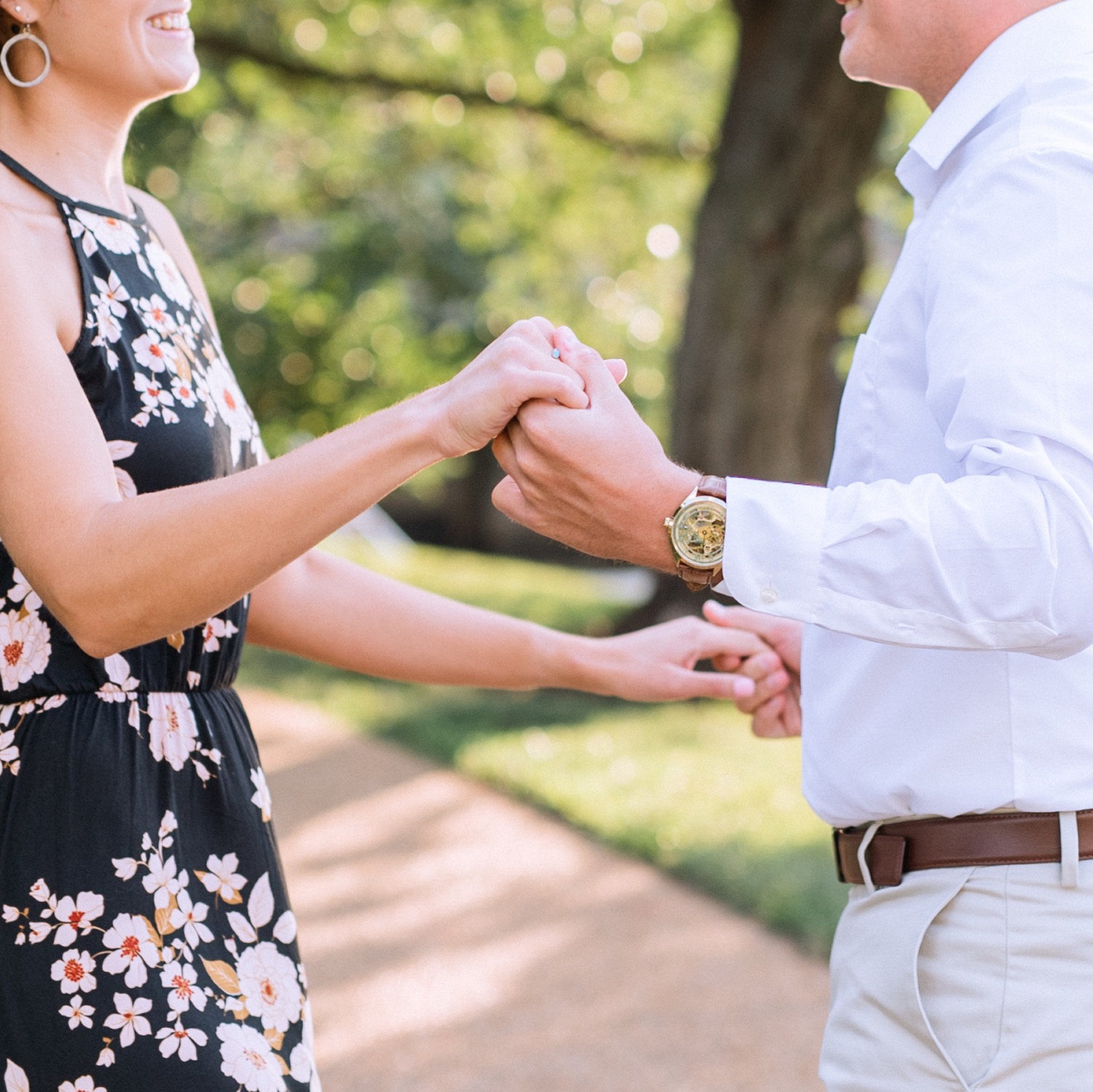 close up of engaged couple holding hands and smiling at each other