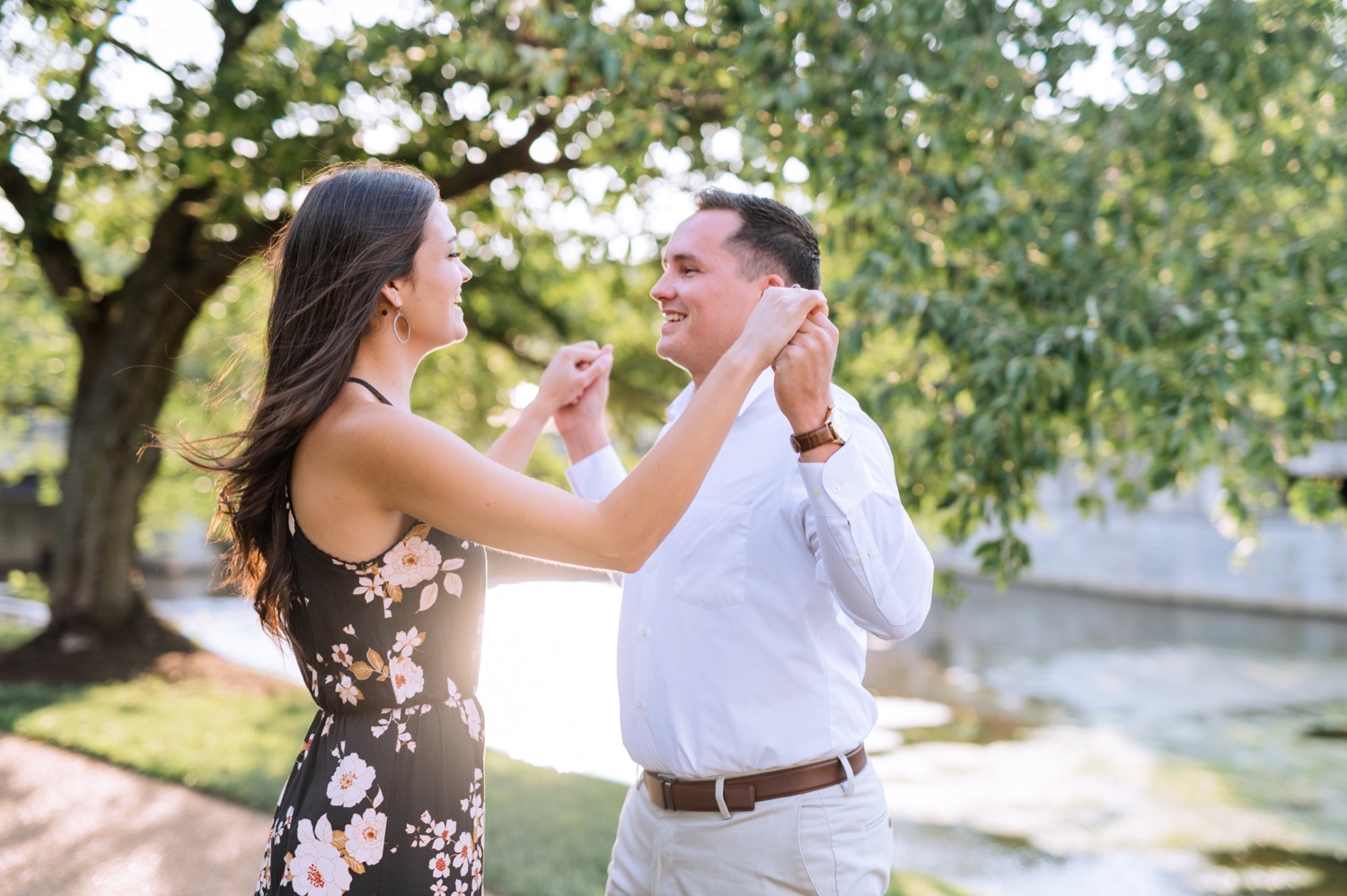 engaged couple twirling and dancing under the trees along a path in browns island outside of richmond virginia 