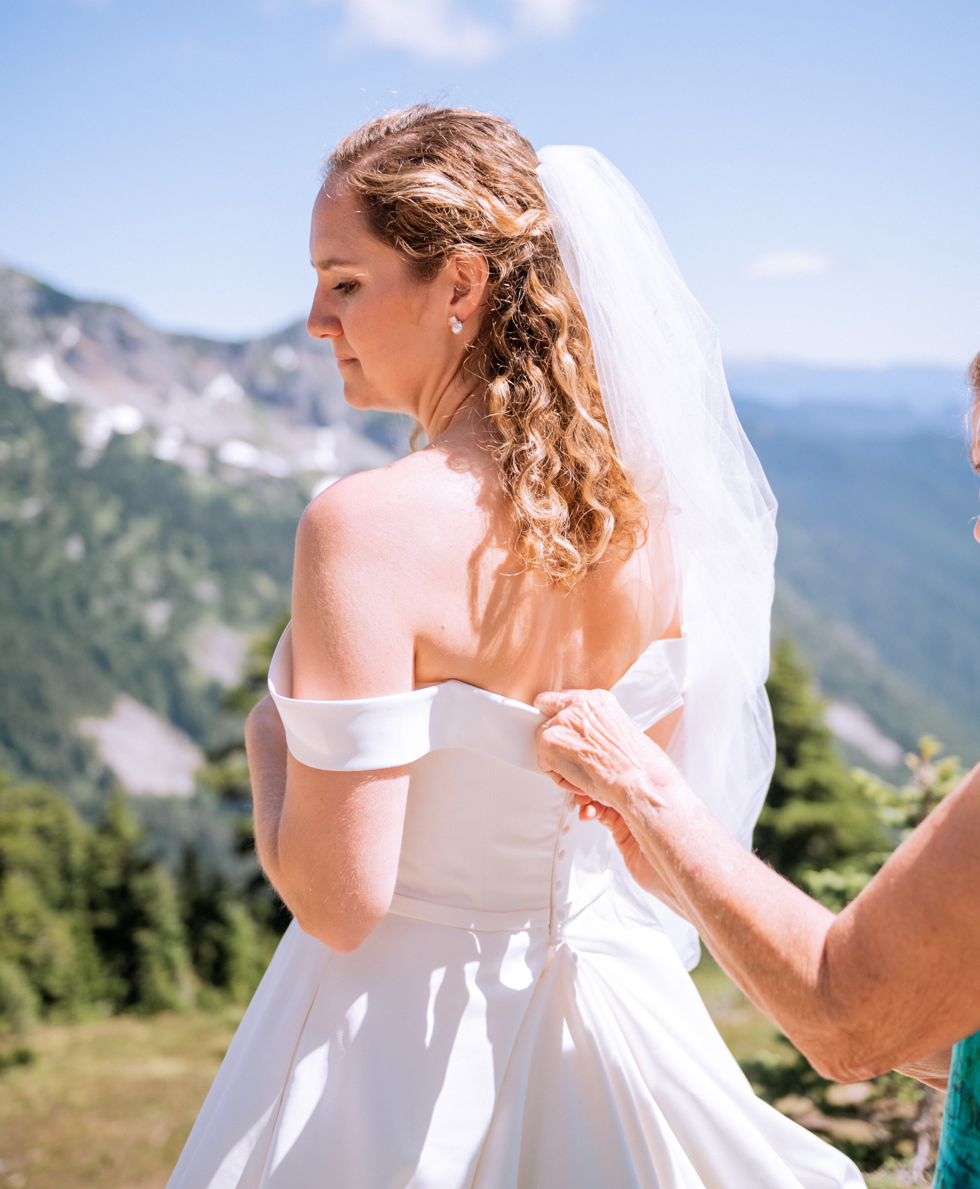 bride looking off into the distance while mother helps her finish getting ready for elopement ceremony