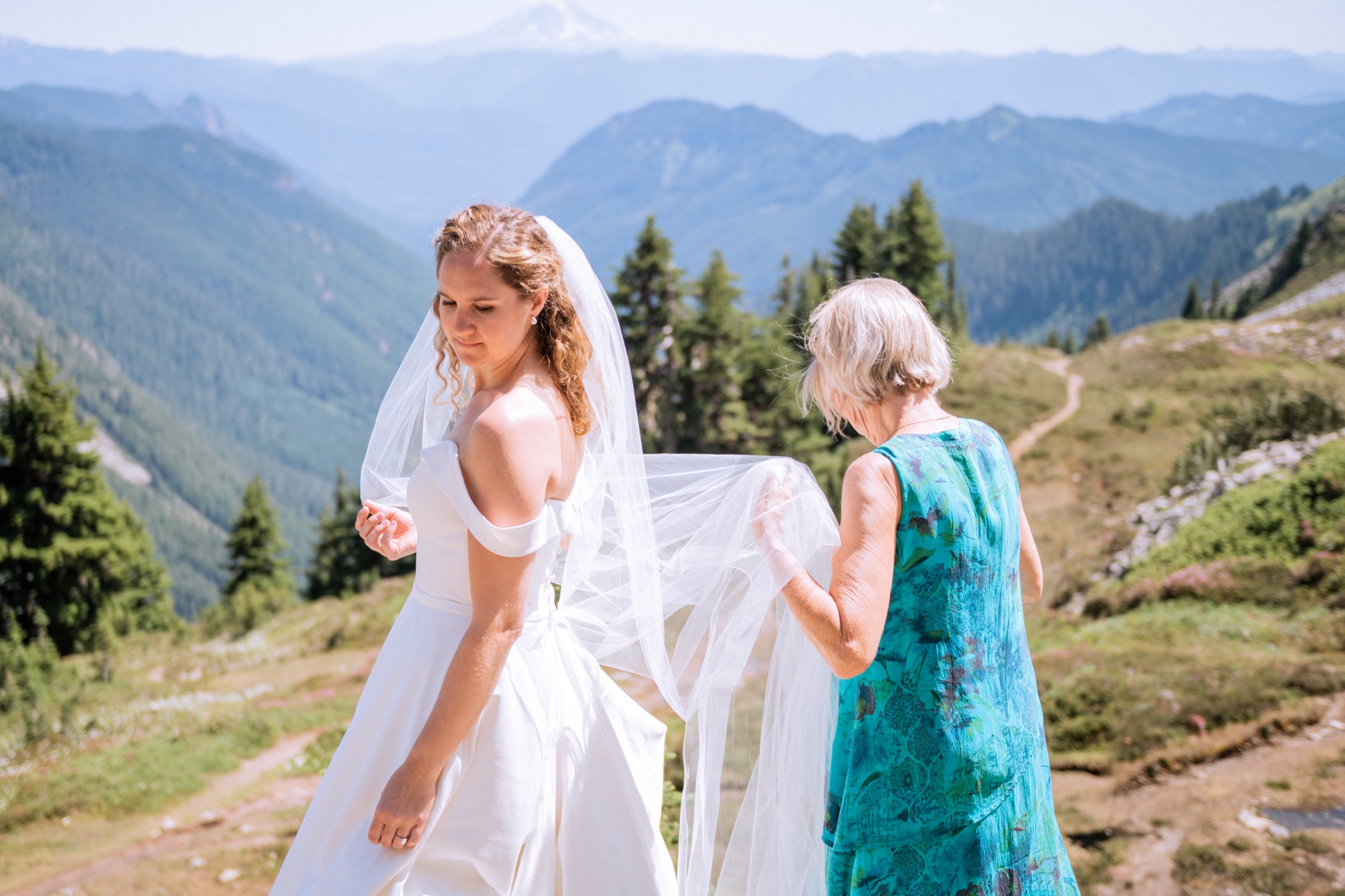 bride in wedding dress and veil with her grandma on top of mt rainier