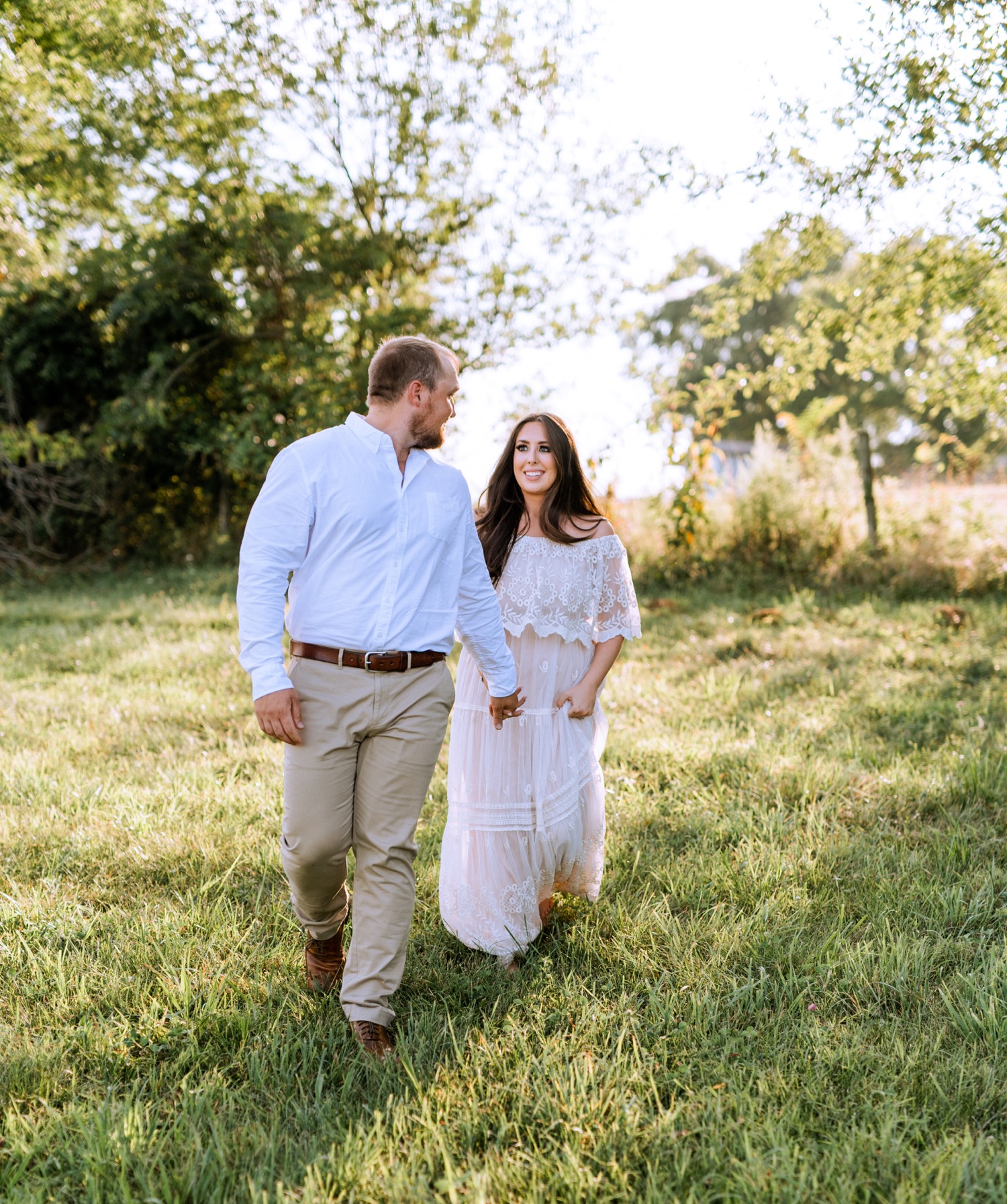 engaged couple holding hands and walking through the rolling hills and fields