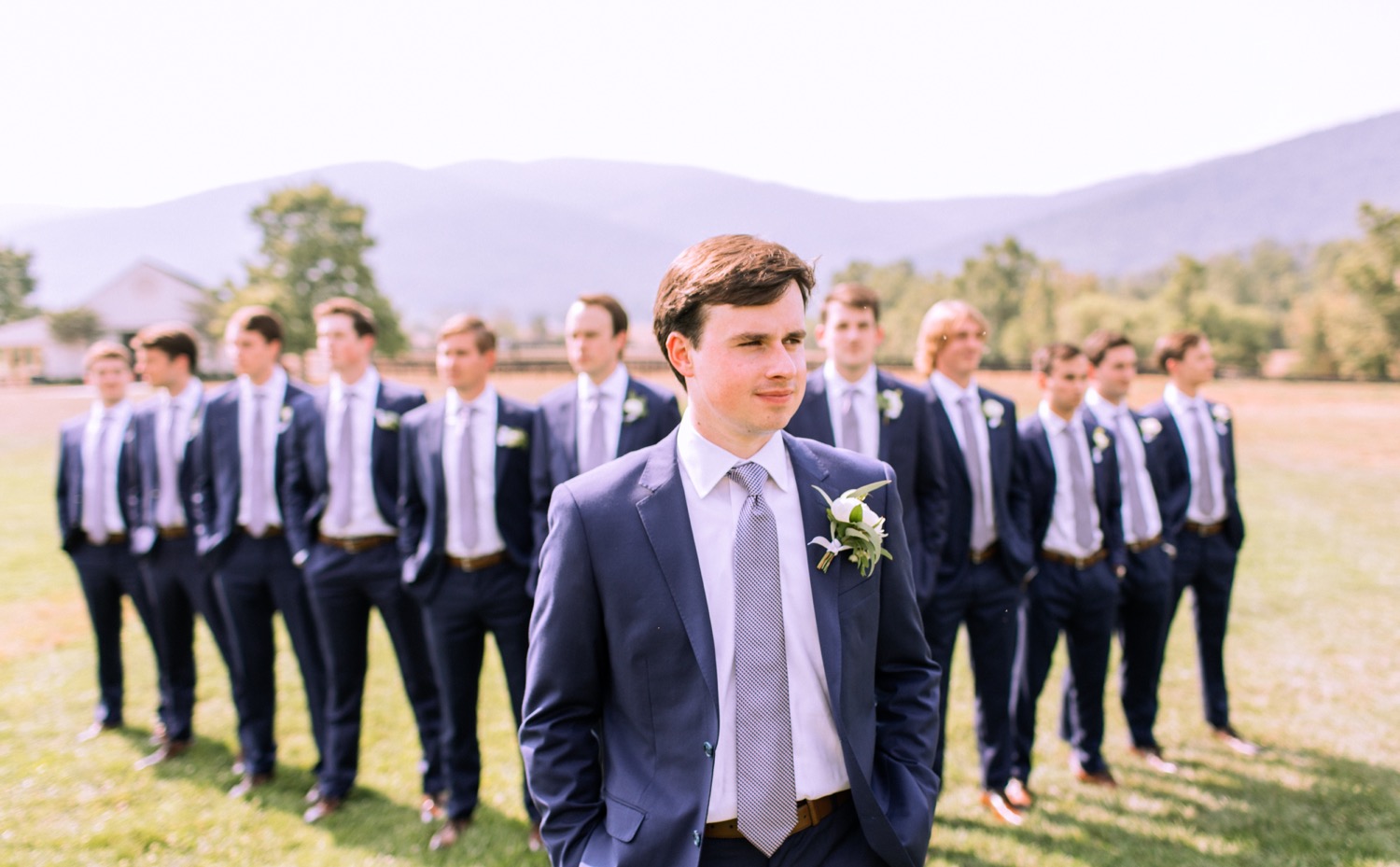 groom looking off into the distance with his groomsmen behind him in their blue suits