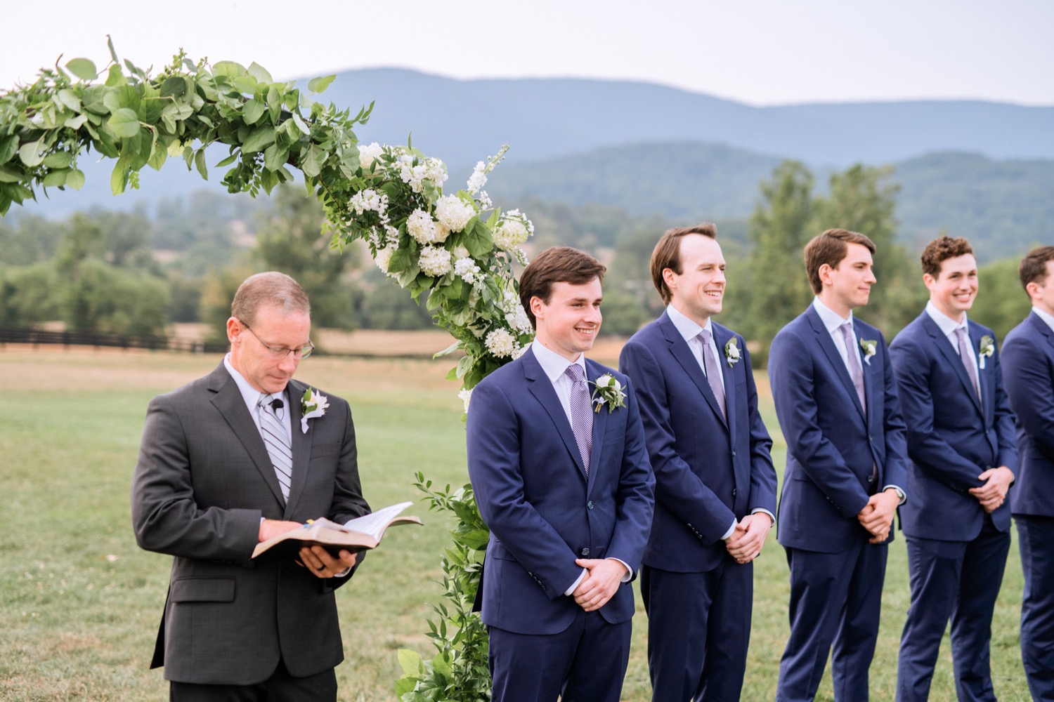 pastor, groom, and groomsmen standing at the alter as the bride walks towards them