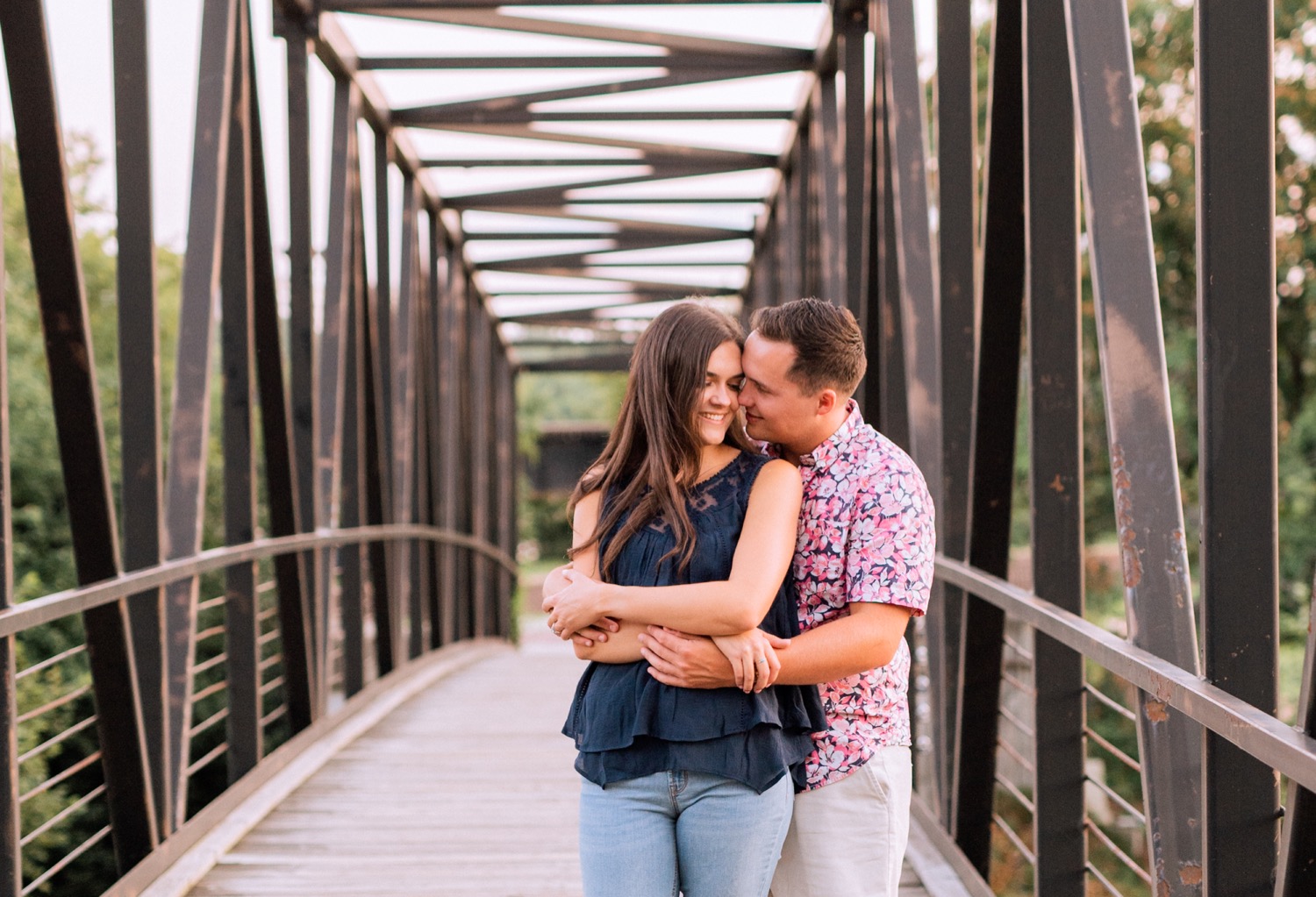 engaged couple wearing casual clothes walking and hugging on the bridge in browns island outside of richmond virginia 