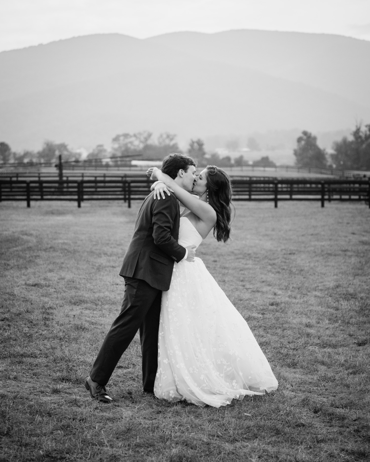 bride and groom sharing a kiss with the mountains and vineyard behind them on their wedding day in Charlottesville, VA
