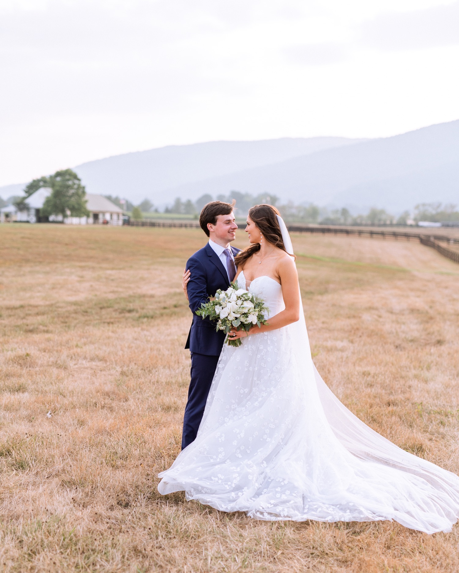 bride and groom look into each others eyes with the vineyard and mountains behind them