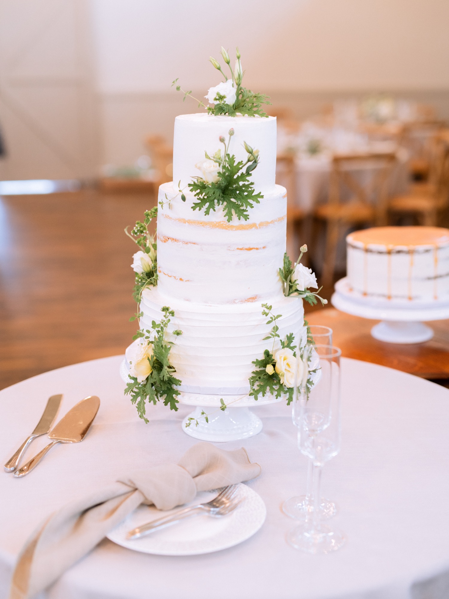 3 tiered white cake with white and green floral arrangements as decoration
