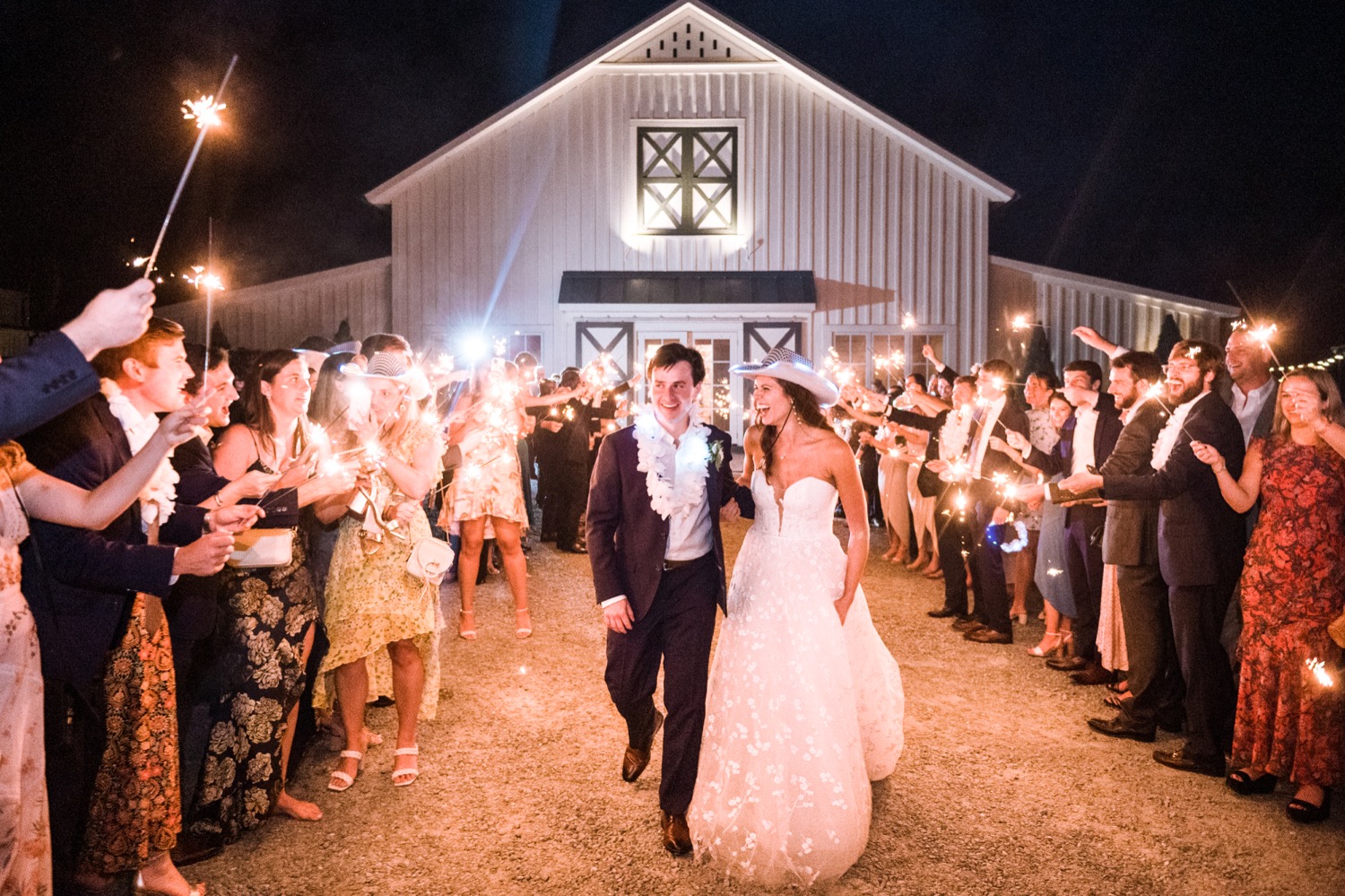 sparkler sendoff with the bride and groom walking through their friends and family with the King Family Vineyard barn behind them