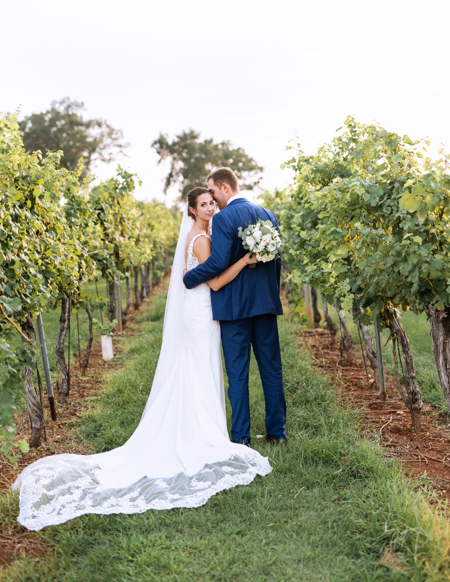 bride and groom walking through keswick vineyards on their wedding day