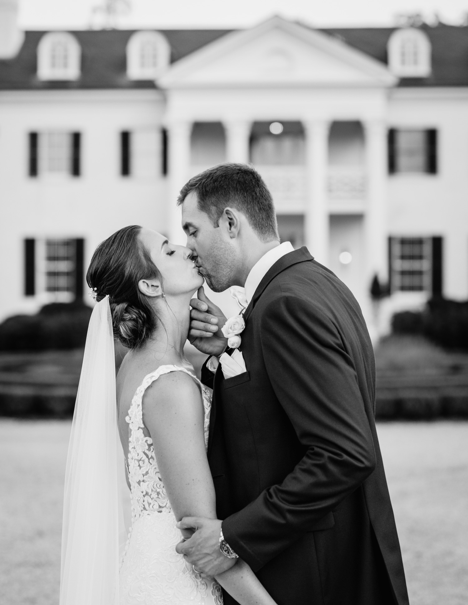 bride and groom kissing in front of the white mansion at keswick vineyards