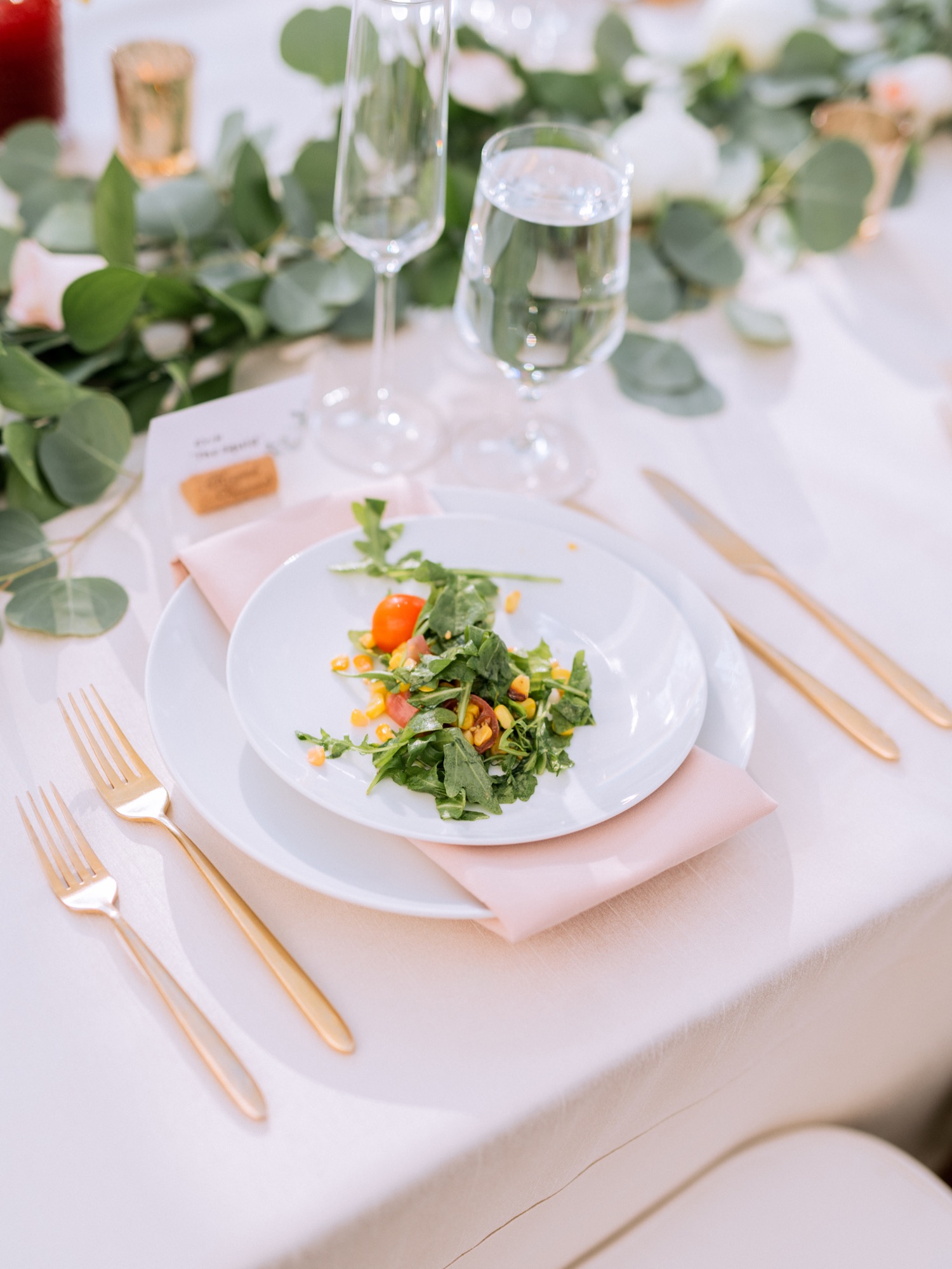 gold silverware and white plates with a salad at a wedding reception taking place at keswick vineyards