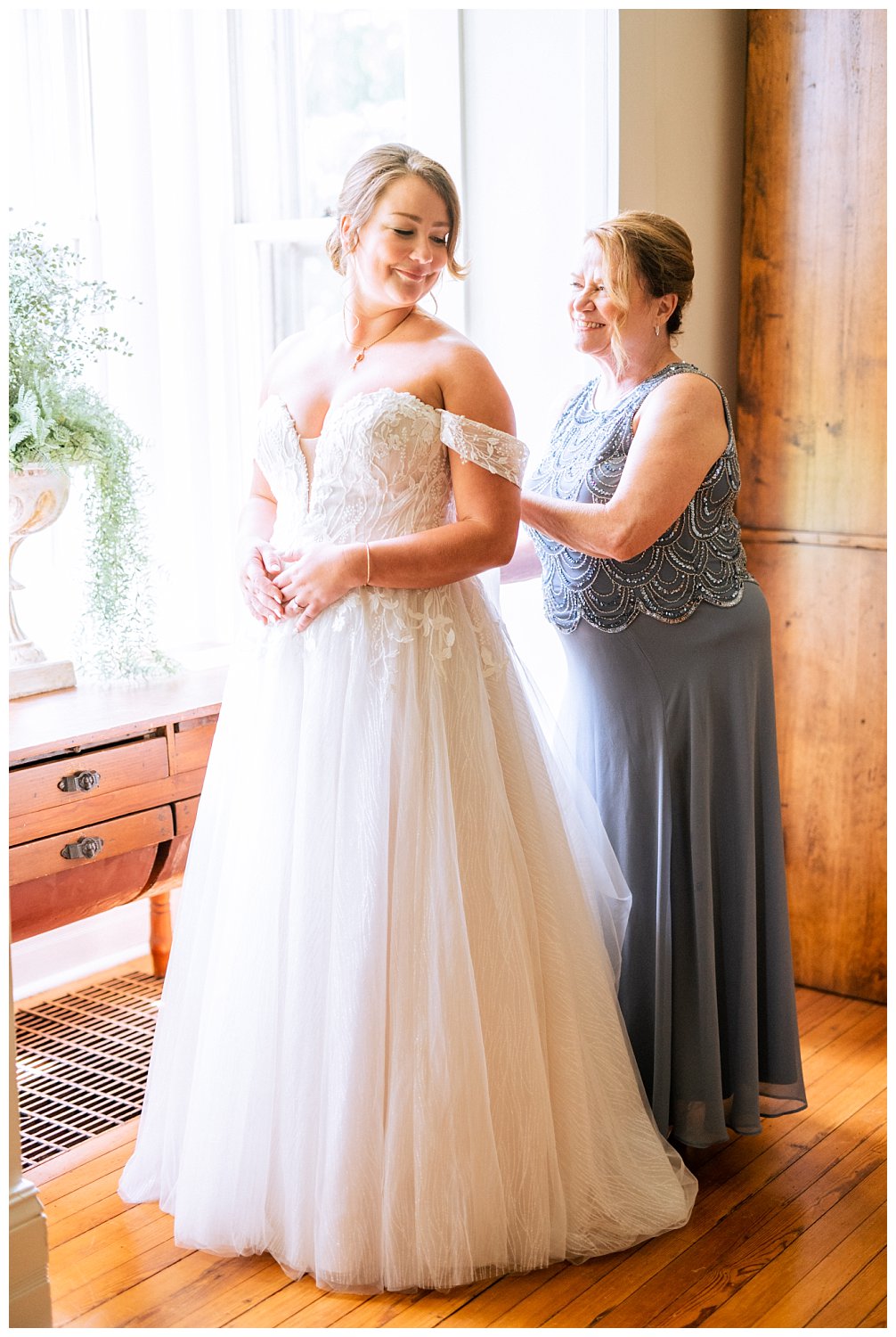 Mother of the bride helping her daughter button up her gown