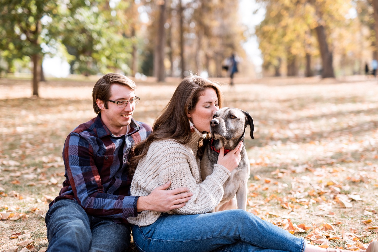 engaged couple cuddling and kissing their dog during engagement photoshoot