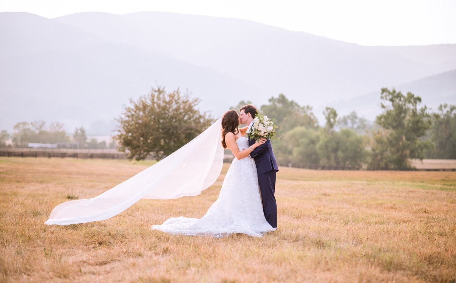 bride and groom sharing a kiss with the mountains and vineyard behind them on their wedding day in Charlottesville, VA