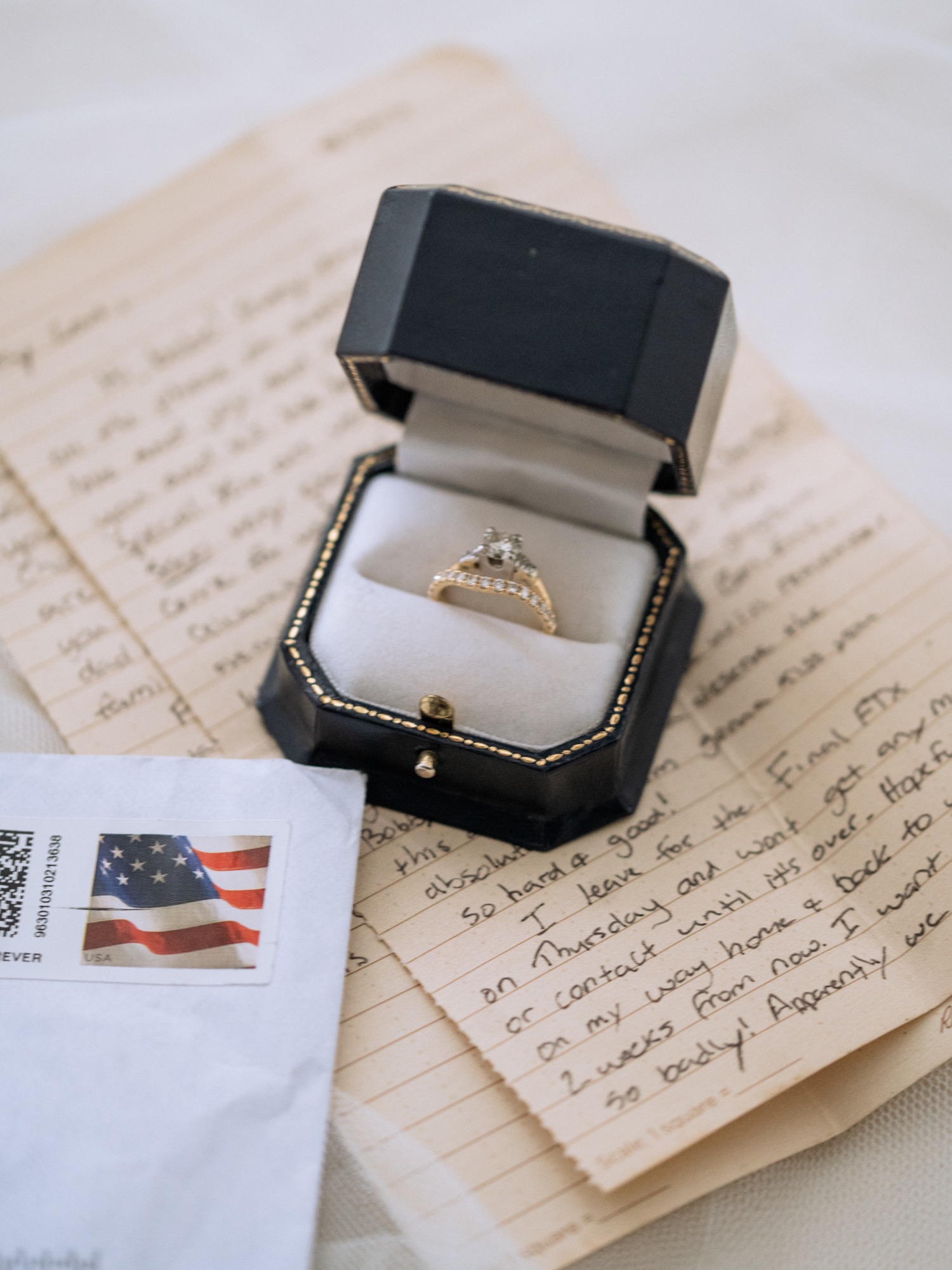 wedding ring in jewelry box on top of a handwritten letter